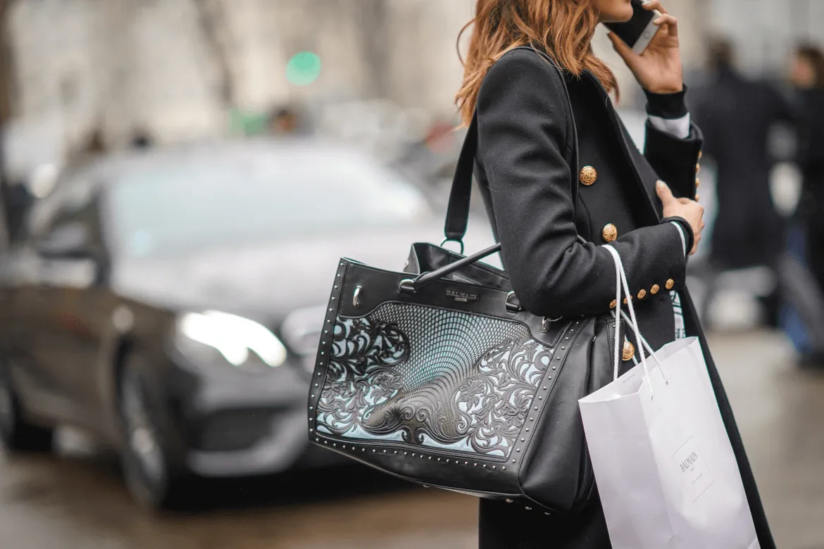 Woman holding black leather Balmain tote bag on city street