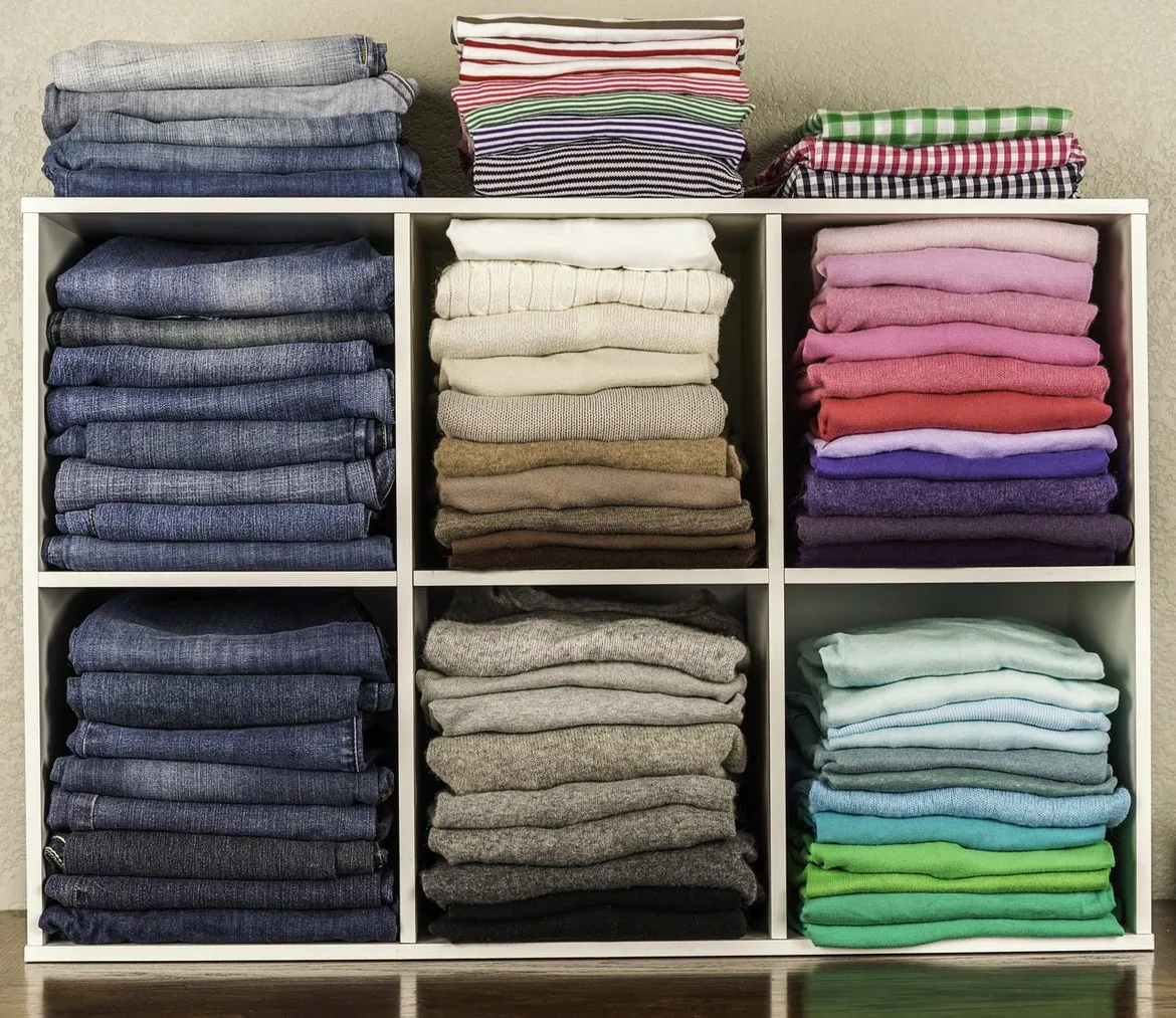 An organized wardrobe with clothes color-coordinated by type and shade