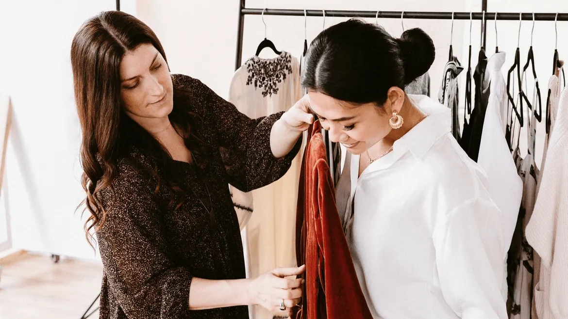 Personal stylist helping woman choose red dress