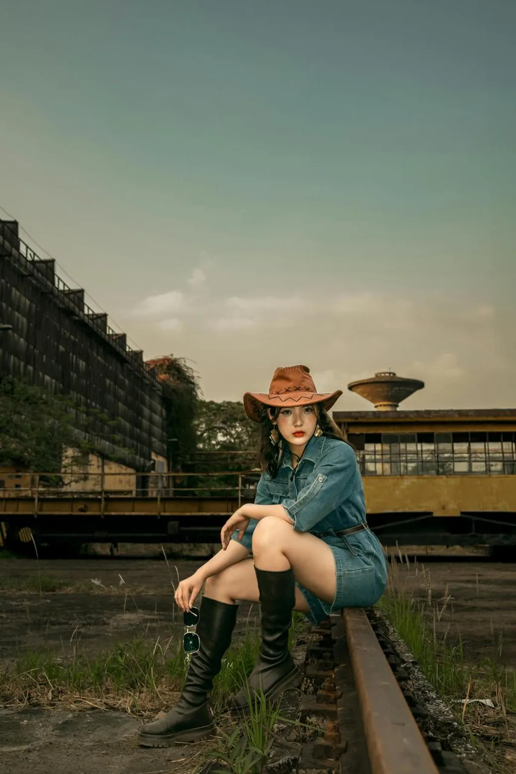 Denim mini dress with cowboy boots and a wide-brim hat