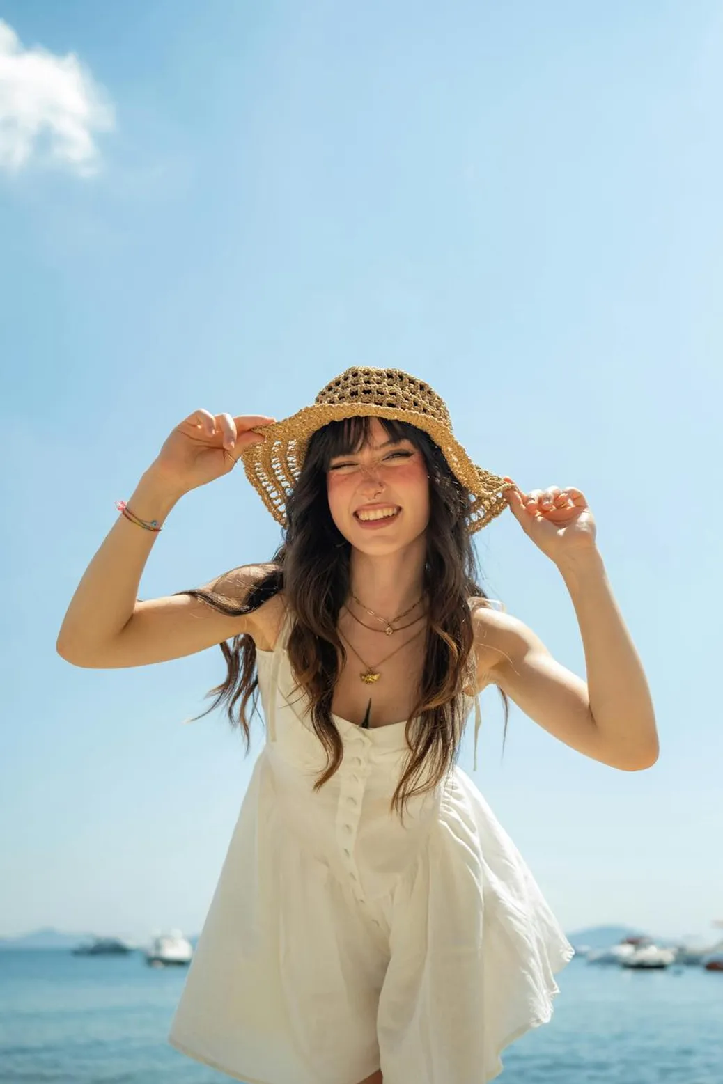 Girl in a white dress with a straw hat at the beach