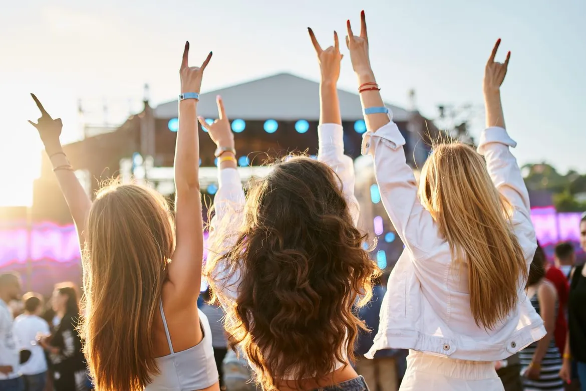 Three girls wearing halter tops and jackets at a music festival