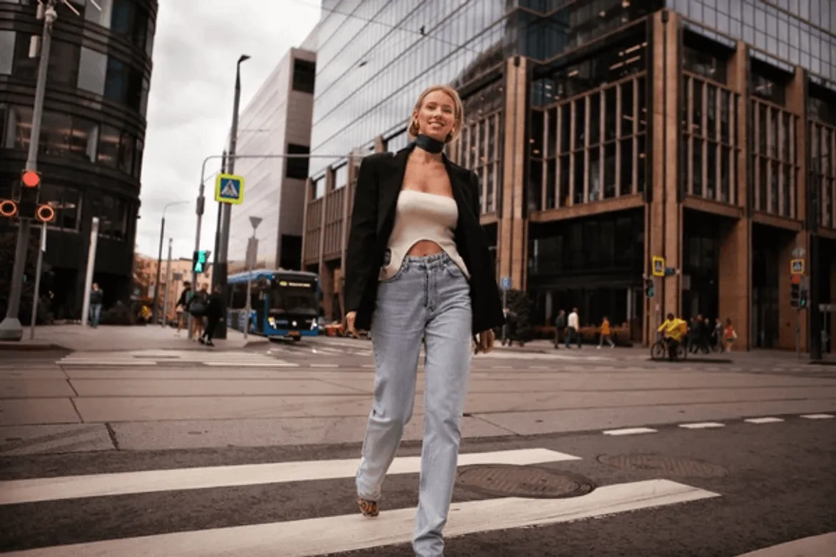 Woman walking in city wearing crop top blazer and jeans