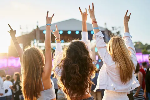 Three girls wearing halter tops and jackets at a music festival